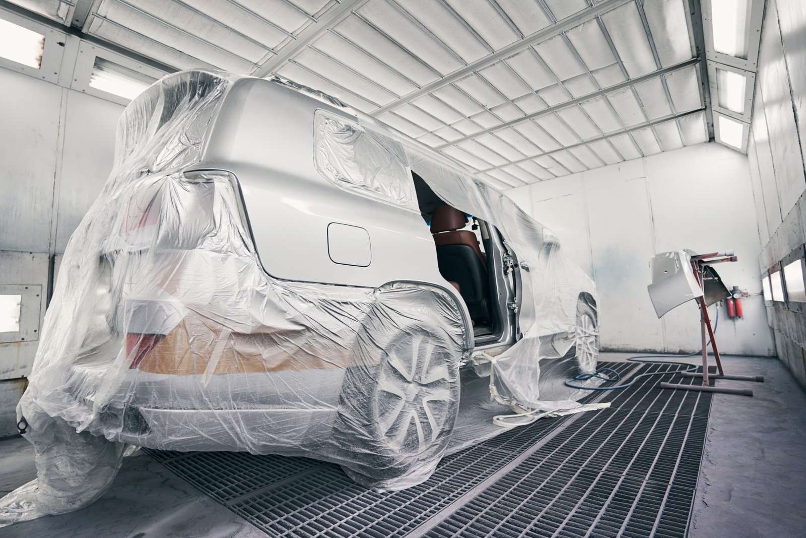 Silver van protected with plastic film from dirt in a spray booth before the start of paint work